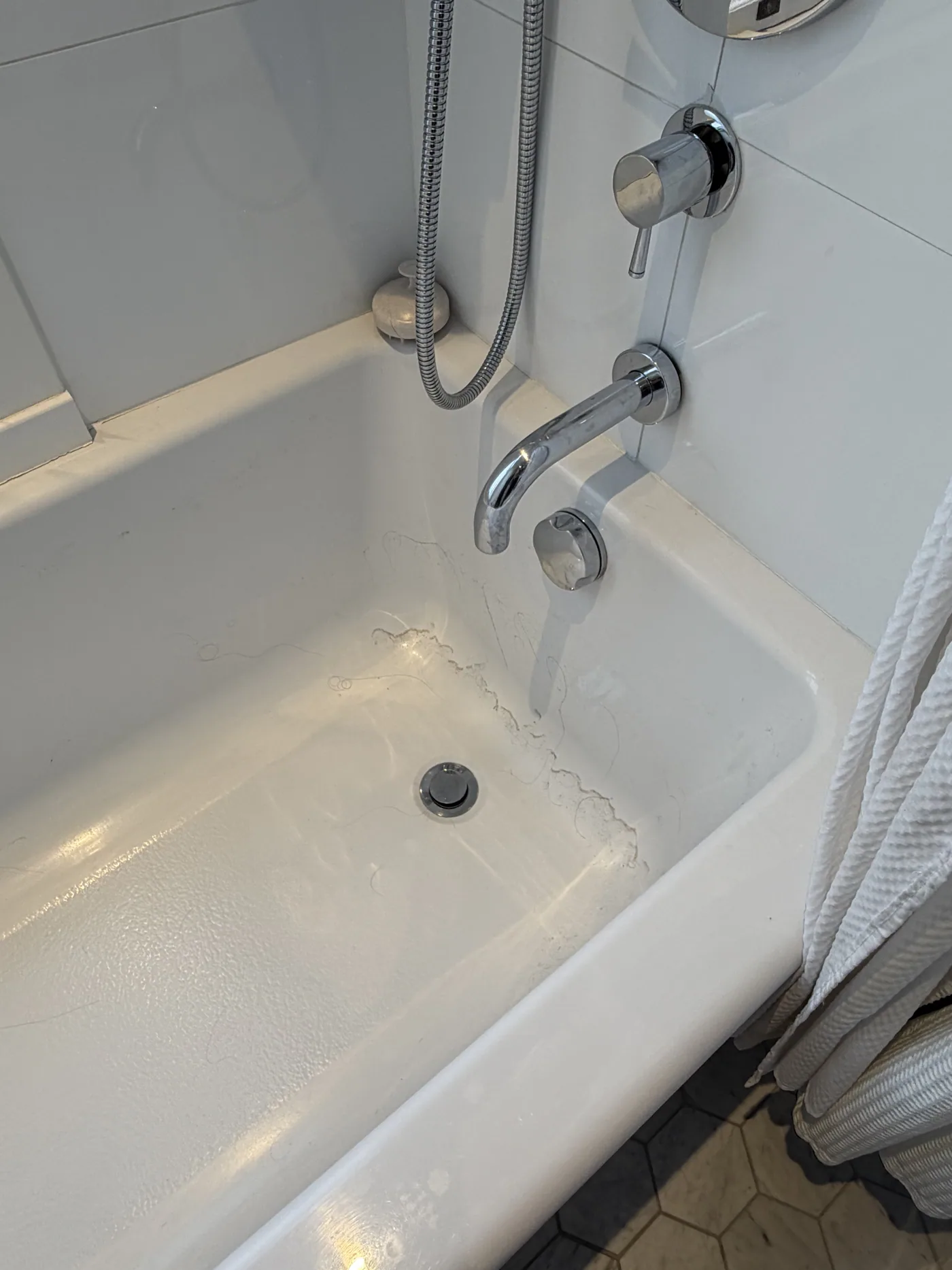 Before: bathtub with soap scum, hair and water marks around the drain
