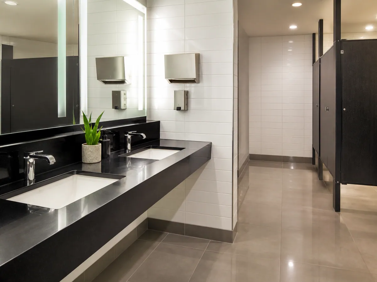 Office restroom with polished vanity, spotless mirrors and sanitised stalls